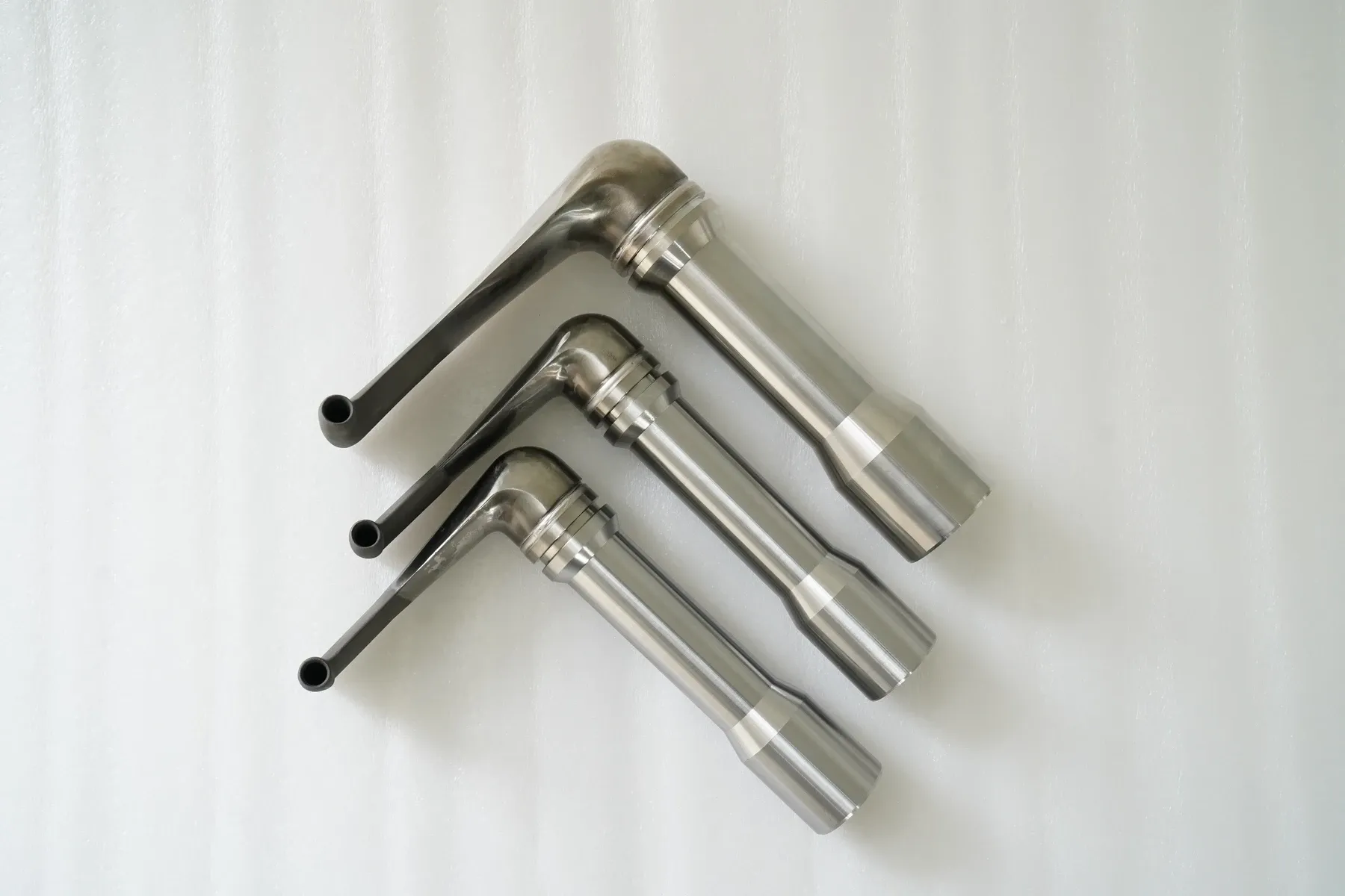 Three stainless-steel pick-up tubes with inlet mouths and outlet passages.